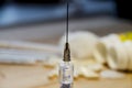 A syringe with a needle on the background of medicines and a wooden table