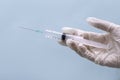 Syringe with a needle on a blue background. Acute medical needle. Nurse holds an injection syringe