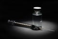 Syringe Needle and Medicine Vaccine Vial Spot Lit on Dark Background