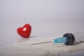 Syringe and pills laid out in the form of heart on a white background.