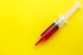 Syringe with red drug on yellow background.