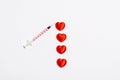 A syringe and several small red hearts in the form of blood drops on a white background. Royalty Free Stock Photo