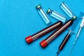 Syringe, test tubes with blood samples and ampoules with medicines or vaccine over blue background