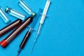 Syringe, test tubes with blood samples and ampoules with medicines or vaccine over blue background