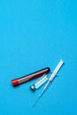 Syringe, test tubes with blood samples and ampoules with medicines or vaccine over blue background