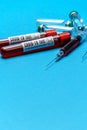 Syringe, test tubes with blood samples and ampoules with medicines or vaccine over blue background