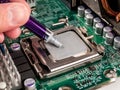 A syringe with thermal paste in his hand is applied to the computer processor to install a cooling radiator with a fan Royalty Free Stock Photo