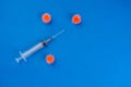 Syringe and three simulated virus on blue background