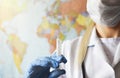 A syringe with a vaccine in the hands of a doctor in protective gloves against the background of a political map. The concept of Royalty Free Stock Photo