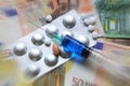 Syringe with vaccine and pills over euro banknotes money. concept image Royalty Free Stock Photo