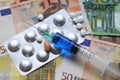 Syringe with vaccine and pills over euro banknotes money. concept image Royalty Free Stock Photo