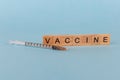 Syringe and the word vaccine from wooden letters on a light blue background. Concept of primary prevention,theme