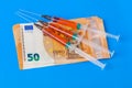 Syringes and euro money on blue background