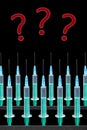 Syringes in rows and red question marks on black background Royalty Free Stock Photo