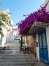 Syros island, Cyclades Greece. Cafe chairs tables at the end of stairs and bougainvillea. Vertical