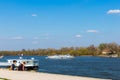 Tourist boat on Szentendre branch of Danube River on sunny day. Family resting on the shore. Space for text Royalty Free Stock Photo