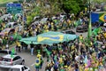 People parade carrying the Brazilian flag along the asphalt with the crowd