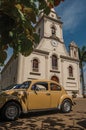 Church facade with parked car and evergreen garden in a sunny day at SÃÂ£o Manuel.