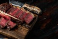 T bone steak is grilled sliced on a piece. Aged Barbecue Porterhouse Steak, on wooden serving board, on old dark wooden table