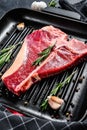 T bone steak in a pan. Organic raw Tbon beef. Black background. Top view