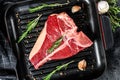 T bone steak in a pan. Organic raw Tbon beef. Black background. Top view