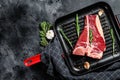 T bone steak in a pan. Organic raw Tbon beef. Black background. Top view. Copy space