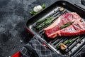 T bone steak in a pan. Organic raw Tbon beef. Black background. Top view. Copy space