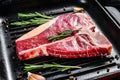 T bone steak in a pan. Organic raw Tbon beef. Black background. Top view