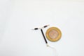 T shape IUD Gold hormon free birth control device beside a coin for size and shape realisation on white background. Selective