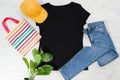 T shirt black. T-shirt Mockup flat lay with summer accessories. baseball hat, bag and denim jeans on wooden floor background. Copy Royalty Free Stock Photo