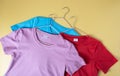 T-shirts on the hangers are blue, red and pink on a yellow background Royalty Free Stock Photo