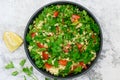 Tabbouleh salad with bulgur, parsley, spring onion and tomato in bowl on grey background. Top view Royalty Free Stock Photo