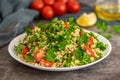 Tabbouleh salad with bulgur, parsley, spring onion and tomato in bowl on grey background. Top view. WIth copy space Royalty Free Stock Photo