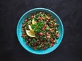 Tabbouleh salad with couscous in a bowl on the black table. Levantine vegetarian salad with parsley, mint, bulgur, tomato. Royalty Free Stock Photo