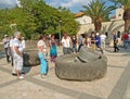 TABGHA, ISRAEL - OCTOBER 06, 2012: Tourists inspect ancient millstones on the territory of the Church of the Multiplication of