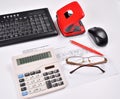 Table accounting: invoice, keyboard, calculator, mouse, hole punch, glasses and red pen Royalty Free Stock Photo