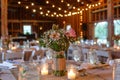 A table adorned with a vase of flowers and candles, part of the rustic barn wedding decorations, A rustic barn wedding with string Royalty Free Stock Photo