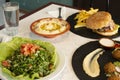 Table with Arabic dishes and a hamburger, falafel, chickpea hummus