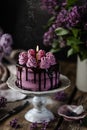 On the table is a beautiful chocolate cake and a bouquet of lilacs. dark