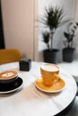 On the table in a beautiful vintage cafe is a black cup with a hot latte and a yellow cappuccino mug. Morning coffee break Royalty Free Stock Photo