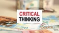 On the table are bills, a bundle of dollars and a sign on which it is written - CRITICAL THINKING. Finance and economics concept Royalty Free Stock Photo