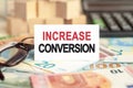 On the table are bills, a bundle of dollars and a sign on which it is written - INCREASE CONVERSION. Finance and economics concept