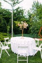 Table with bouquet and chairs around it are on at wedding banquet in lawn at garden Royalty Free Stock Photo