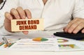 On the table are business charts and diagrams in the hands of a wooden block with the inscription - JUNK BOND DEMAND