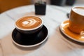 On the table in the cafe is a black cup with a hot latte and a yellow mug with cappuccino. Morning coffee break in the coffee shop Royalty Free Stock Photo