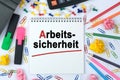 On the table is a calculator, diary, markers, pencils and a notebook with the inscription - Arbeits-sicherheit