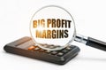 On the table is a calculator and a magnifying glass, inside which the inscription - Big Profit Margins Royalty Free Stock Photo