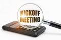 On the table is a calculator and a magnifying glass, inside which the inscription - Kickoff Meeting Royalty Free Stock Photo