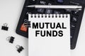 On the table is a calculator, a pen and a notebook with the inscription - MUTUAL FUNDS