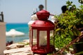 Red small lantern as decoration at a seacoast restaurant.able in cozy outdoor cafe with a small lantern and plant Royalty Free Stock Photo